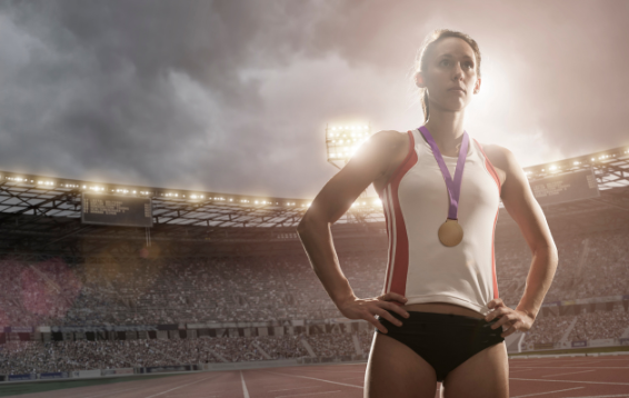 Athlete wearing an Olympic medal with crowded stadium in background 
